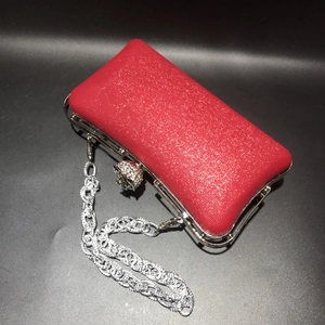 Detail of red glitter evening clutch with rhinestone clasp and silver chain strap