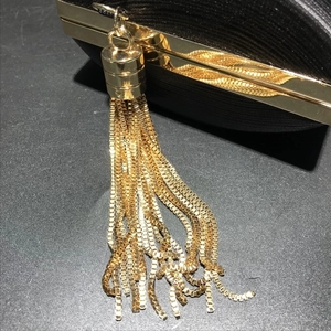 Detail of the golden metal tassel and fine black fabric texture on this evening clutch