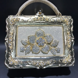 Detailed close-up of a gold evening clutch featuring crystal floral patterns and metal frame