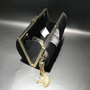 Detail of black satin pleated evening bag with gold trim and long tassel charm