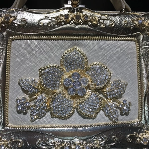 Macro shot of gold evening clutch featuring a large rhinestone flower and metal carvings