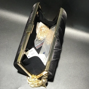 Detailed open view of black silk evening clutch bag with gold tassel and metal frame