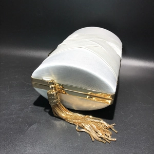 Detail of white satin evening bag featuring gold fringe tassel and woven silk texture