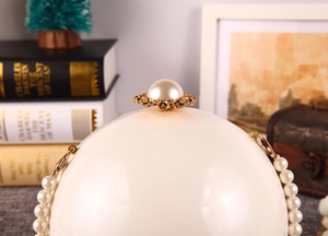Détail de pochette sphérique en perles avec fermoir floral doré et chaîne de perles