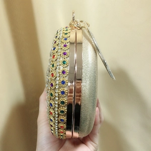 Golden oval clutch bag with colorful rhinestones and metal ring handle for evening events