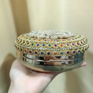 Detailed close-up of colorful rhinestones and jewels on a gold round evening clutch bag