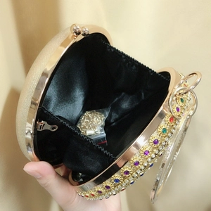 Detail of round gold clutch with multi-colored rhinestones and internal gold chain strap
