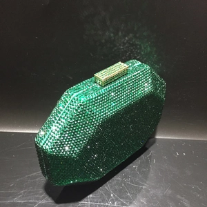 Detail view of octagon green rhinestone clutch bag with gold clasp on black background