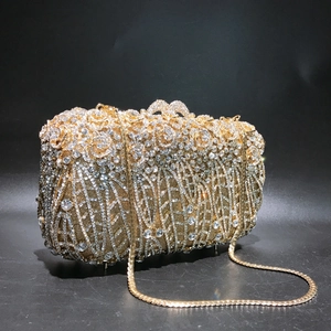 Close-up of golden evening clutch with crystal flower patterns and metal chain strap