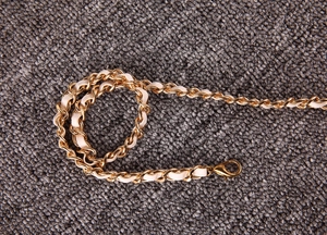 Détail de la bandoulière chaîne en métal doré et cuir blanc avec fermoir mousqueton