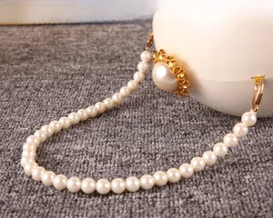 Vue détaillée d'une chaîne en perles avec fermoir doré sur un sac sphérique blanc élégant