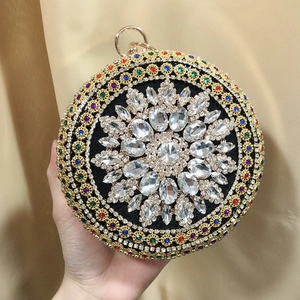 Close-up of a luxury round evening bag with colorful crystals and a gold ring handle
