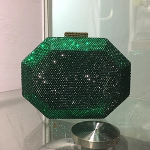 Macro view of green rhinestone encrusted octagonal clutch bag with golden metal clasp