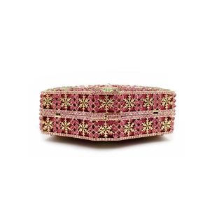 Macro detail of champagne gold evening clutch with pink and green snowflake crystal patterns