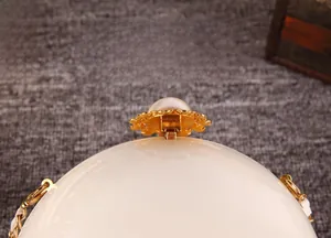 Détail macro d'un sac de soirée perle blanc rond avec fermoir doré élégant