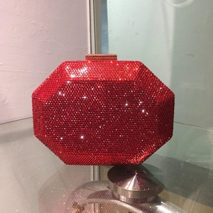 Detailed view of red rhinestone evening clutch with octagonal shape and gold clasp
