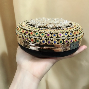 Detailed close-up of a round evening clutch bag with colorful rhinestones held in hand