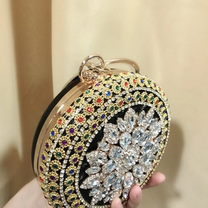 Detail of round evening clutch featuring colorful crystals and diamond finger ring handle