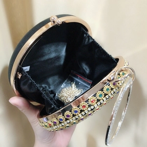 Detail view of round velvet evening bag with colorful rhinestones and gold ring handle