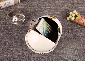 Vue détaillée de l'embrayage rond en acrylique ivoire contenant un iPhone et des accessoires