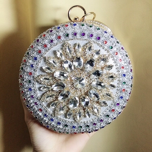 Macro shot of circular evening bag with colorful rhinestones and gold ring handle