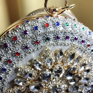 Macro shot of silver evening bag with colorful crystals and circular handle details