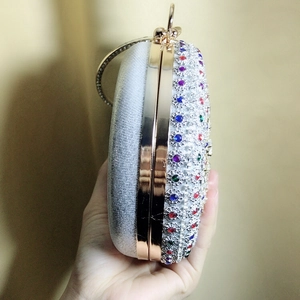 Detail of round dinner clutch with colorful crystals and gold metal ring handle