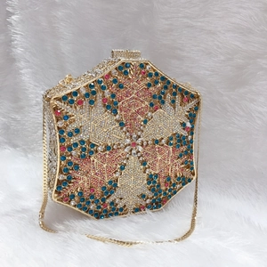 Detail of a hexagonal evening bag with colorful crystals and a gold chain strap