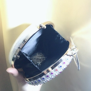 Detail of round evening clutch with colorful rhinestones, metal chain and black lining