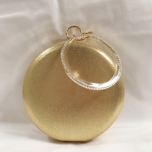 Close-up of golden clutch bag with rhinestone-encrusted round metal handle and satin finish
