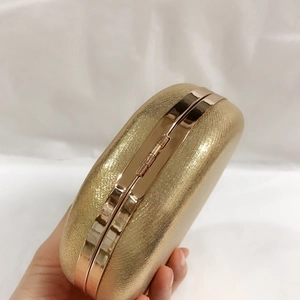 Detail of golden evening clutch bag with glitter texture and metallic frame