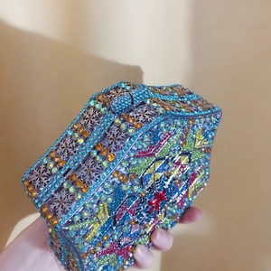 Detailed view of handmade geometric snowflake patterns with colorful crystals on clutch