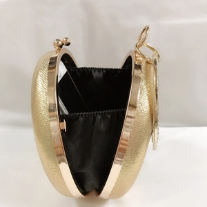 Detail showing internal capacity of gold glitter round evening bag with a phone inside