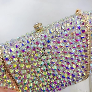 Macro detail of luxury evening clutch bag featuring iridescent AB crystals and gold chain
