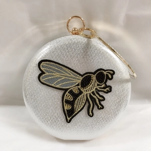 Detailed silver evening clutch bag with bee embroidery and gold metal ring handle