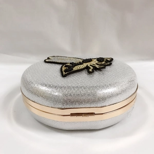 Macro detail of silver sequined evening clutch with honeybee embroidery and metal frame