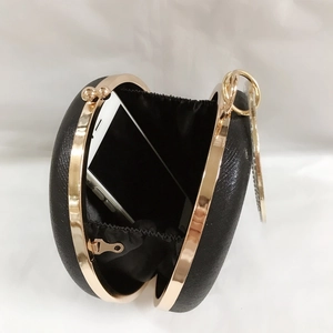 Detail view of round black PU clutch bag interior with gold ring handle and phone storage