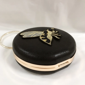 Close-up of beaded bee embroidery on black round evening clutch with diamond ring handle