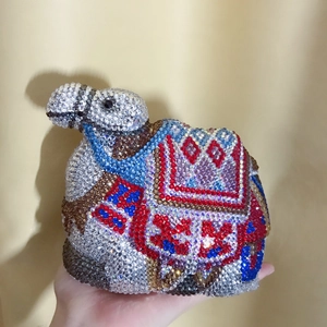 Detailed view of hand-held camel shaped evening bag encrusted with colorful crystals