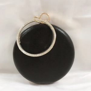 Close-up of black satin clutch with rhinestone-studded circular handle and gold hardware