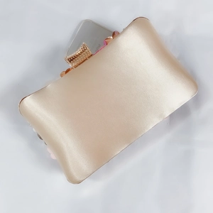 Detail of champagne satin evening clutch with 3D floral accents and gold metal clasp