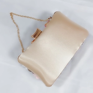 Close-up of champagne satin evening bag with floral embroidery and diamond clasp