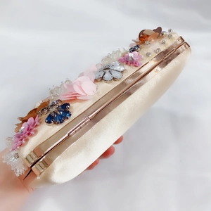 Close-up of champagne satin evening clutch with 3D floral beadwork and crystals