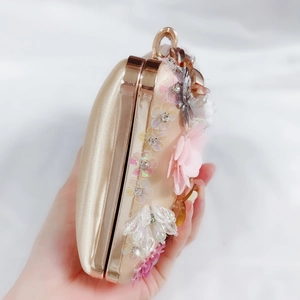 Detail of champagne satin evening clutch with 3D chiffon flowers, beads and crystals