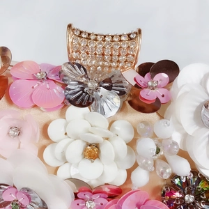 Detail of evening clutch featuring 3D sequin flowers and sparkling rhinestone clasp