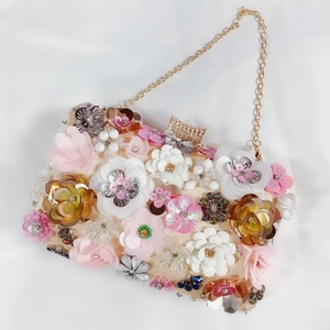 Detail of peach satin clutch bag with 3D sequin flowers and gold chain strap