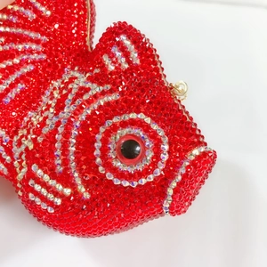 Gros plan sur les strass rouges et argentés de la pochette de soirée en forme de poisson