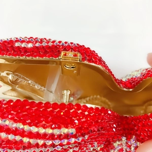 Détail macro du fermoir doré et des strass en cristal rouge de la pochette en forme de cœur