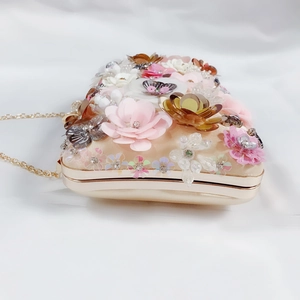 Detailed close-up of champagne satin clutch with 3D floral sequins and crystals