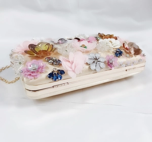 Detailed close-up of champagne satin evening clutch with 3D floral petals and crystals